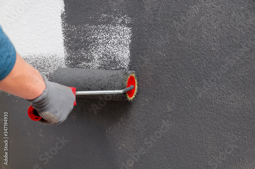Girl holds a roller in hand close-up. Girl repaints the wall in gray. Repair in the room. DIY repair.