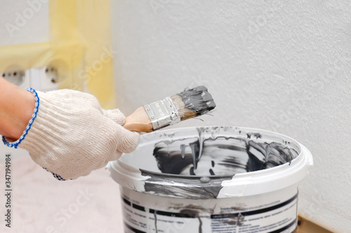Girl repaints the wall in gray. Repair in the room. DIY repair.