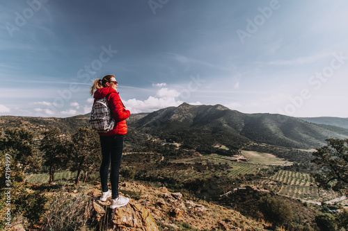 Woman with backpack enjoying view at mountain tops, young traveller alone enjoying trekking through mountains, solo tourism, hiking adventure
