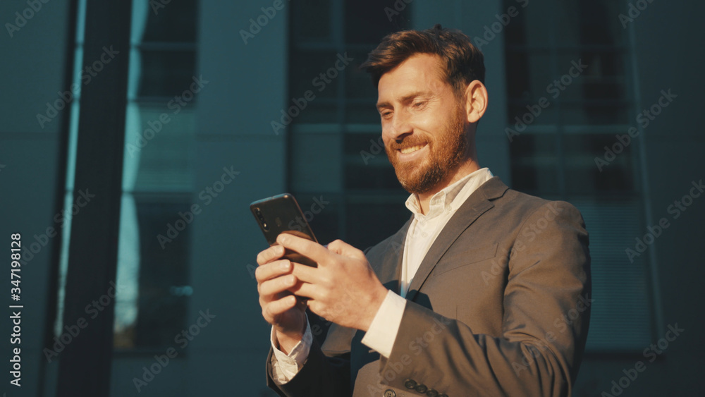 Shot move around businessman stand in the city center street uses phone texting scrolling tapping smile technology communication sunny day success slow motion Shot move around businessman stand in the city center street uses phone texting scrolling tapping smile technology communication sunny day success slow motion