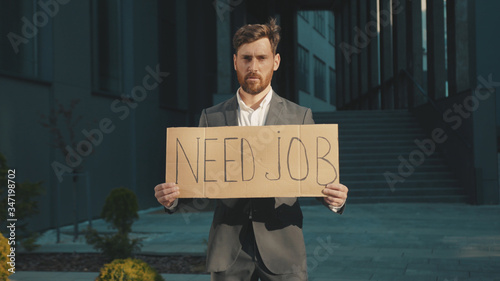 Portrait young businessman holding poster cardboard with Need Job jobless message sign coronavirus crisis text job showing professional finance economy slow motion