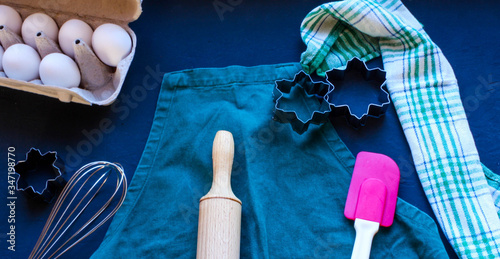 Baking utensils and ingredients are spread out on the dark surface.