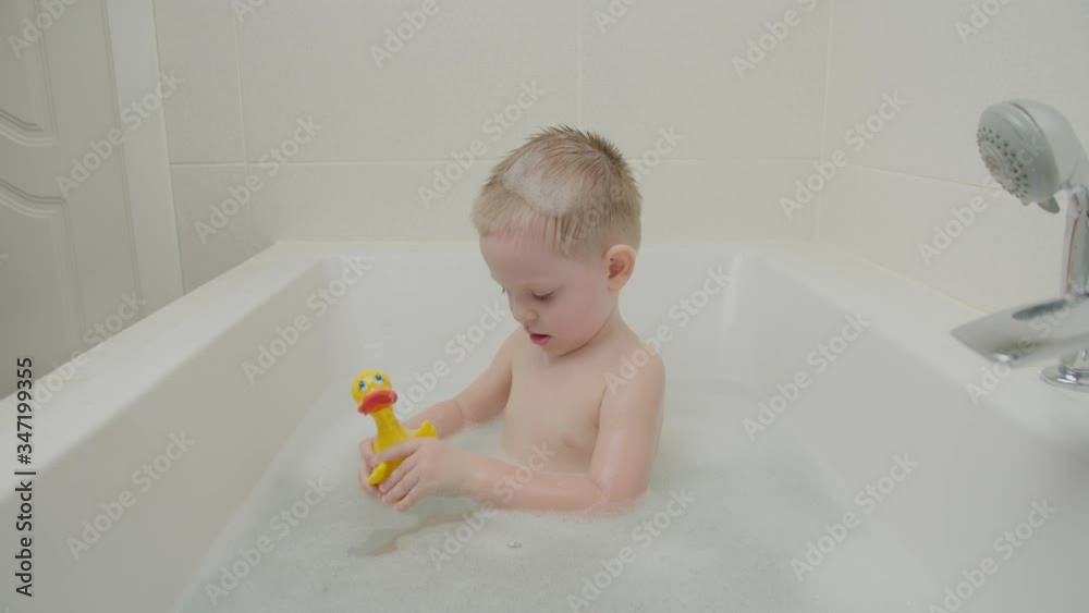 Cheerful wonderful boy playing in the bathroom with foam and toys. Baby with blue eyes and blond. Cheerful wonderful boy playing in the bathroom with foam and toys. Baby with blue eyes and blond.