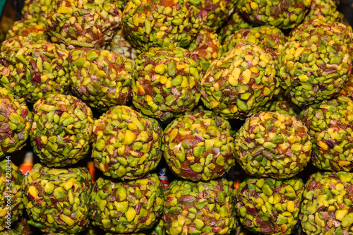 Turkish fruit and nut balls candy. Scattered pistachio and almond nuts