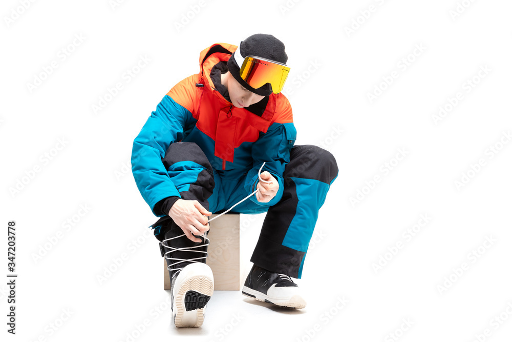 Portrait young man in sportswear with snowboard fastens boots isolated white background