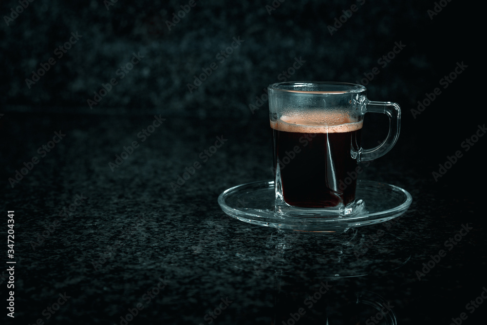 Front view of glass cup with creamy coffee, grey and dark background. Front view of glass cup with creamy coffee, grey and dark background.