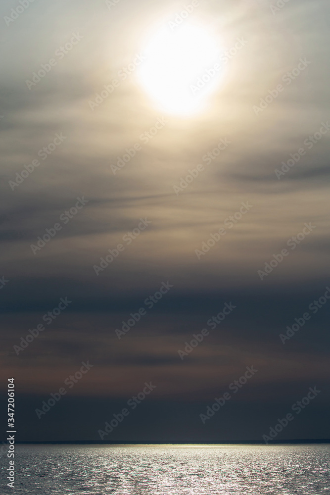 Sunset over the ocean with soft clouds under the sun