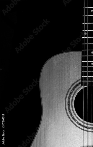 Acoustic guitar close-up view with a black background. Selective focus. b&w.