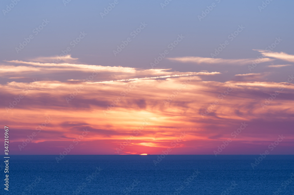 Vibrant sunset over the ocean on a partly cloudy day in summer