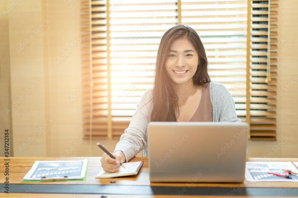 Asian beautiful woman smiling using writing on note book reminders and computer laptop video call conference meetings with collogues discussing job at work planning strategy quarantines isolation Asian beautiful woman smiling using writing on note book reminders and computer laptop video call conference meetings with collogues discussing job at work planning strategy quarantines isolation