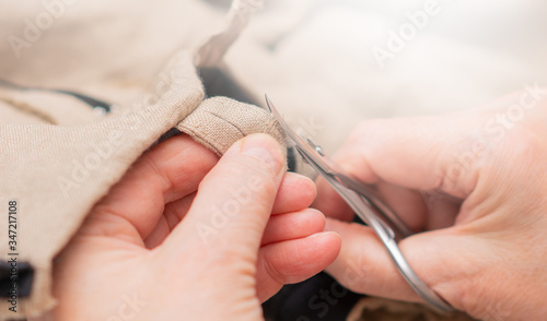 Bilde på lerret Seamstress crop excess of sticking out threads workpiece from clothing by using small scissors