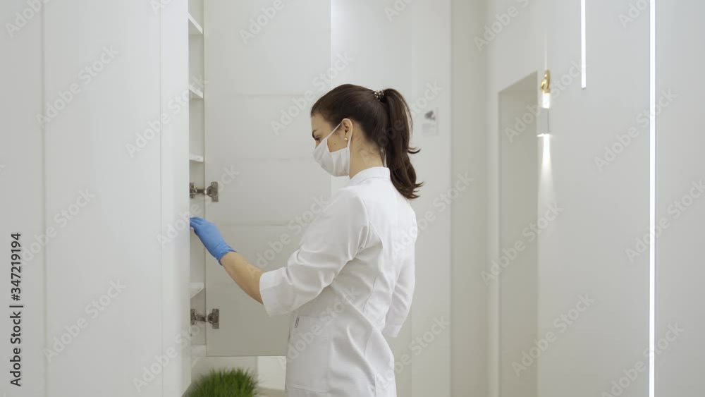 Masked woman searches for medical documents in new modern clinic during quarantine, pandemic Masked woman searches for medical documents in new modern clinic during quarantine, pandemic