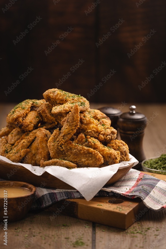 Φωτογραφία Vertical shot of a pile of fried chicken wings and some spices on a wooden table