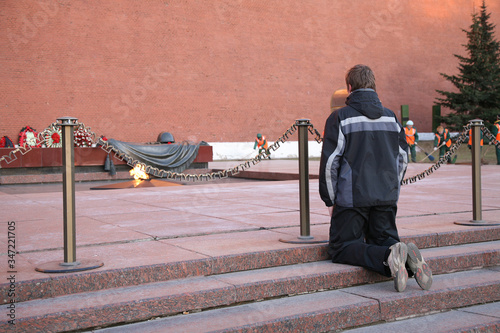 A young man knelt before the eternal flame at the grave of the Unknown soldier-a monument to all those who died in the great Patriotic war. Moscow, Russia photo