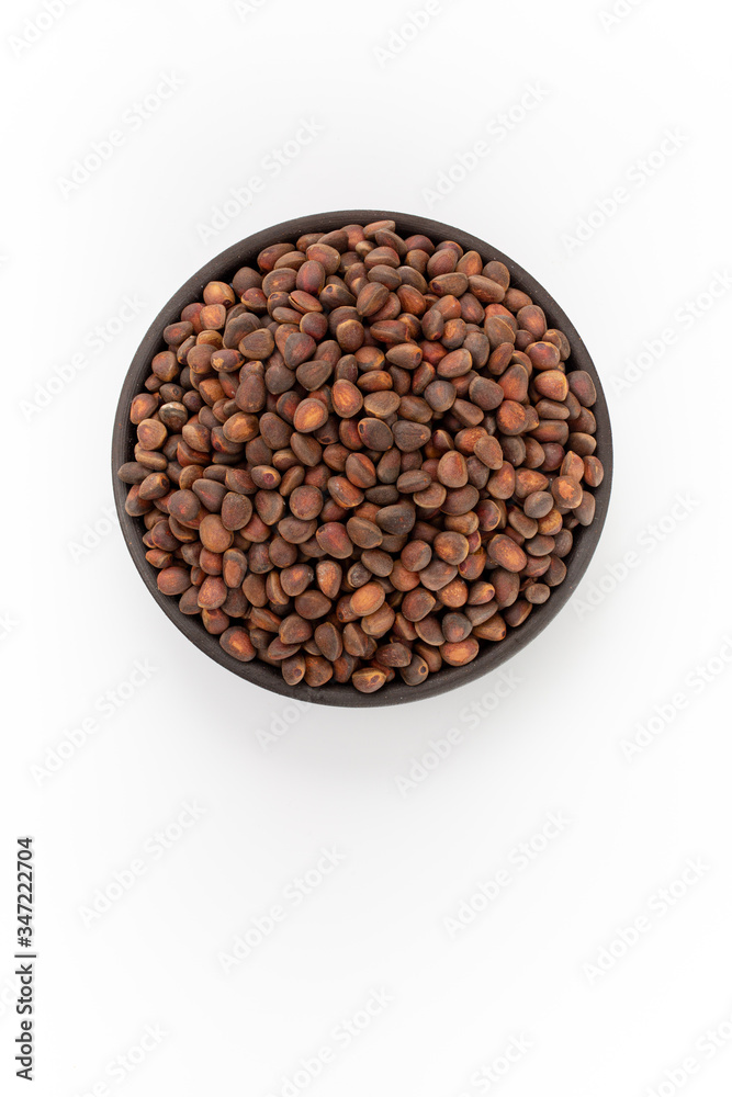 Cedar nuts in round bowl on white background, top view Cedar nuts in round bowl on white background, top view