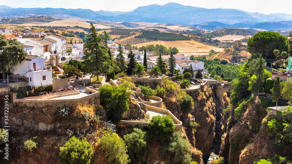 Panoramic view from the bridge of the city of Ronda on the houses, gorge, fields and mountains on the horizon