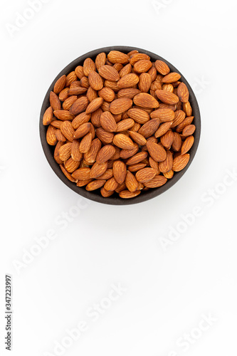 Raw Almonds nuts in round bowl on white background, top view
