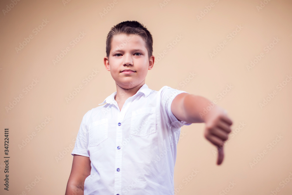 A portrait of kid boy showing thumb down gesture. Childhood and emotions concept A portrait of kid boy showing thumb down gesture. Childhood and emotions concept