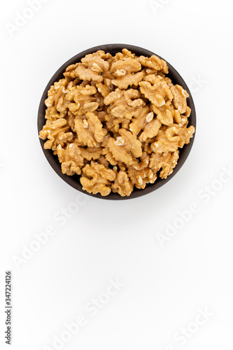 Cleaned Walnuts in round bowl on white background, top view