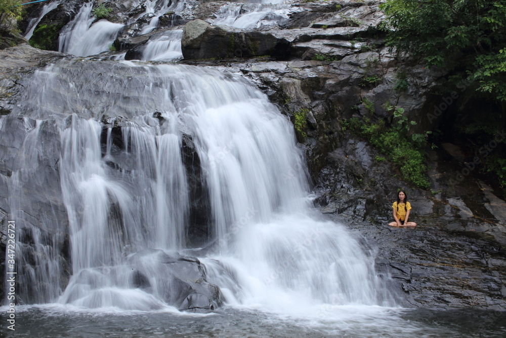 Woman sitting at Khlong Nam Lai waterfall in Klong Lan national park, Kamphaeng Phet, Thailand Woman sitting at Khlong Nam Lai waterfall in Klong Lan national park, Kamphaeng Phet, Thailand