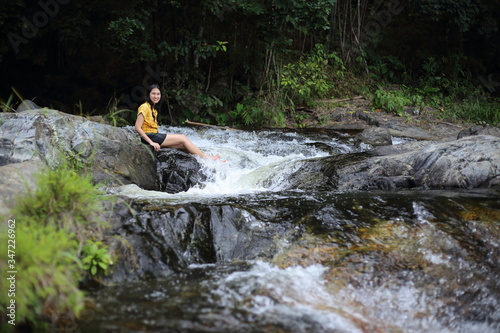 Woman sitting at Khlong Nam Lai waterfall in Klong Lan national park, Kamphaeng Phet, Thailand © pantkmutt