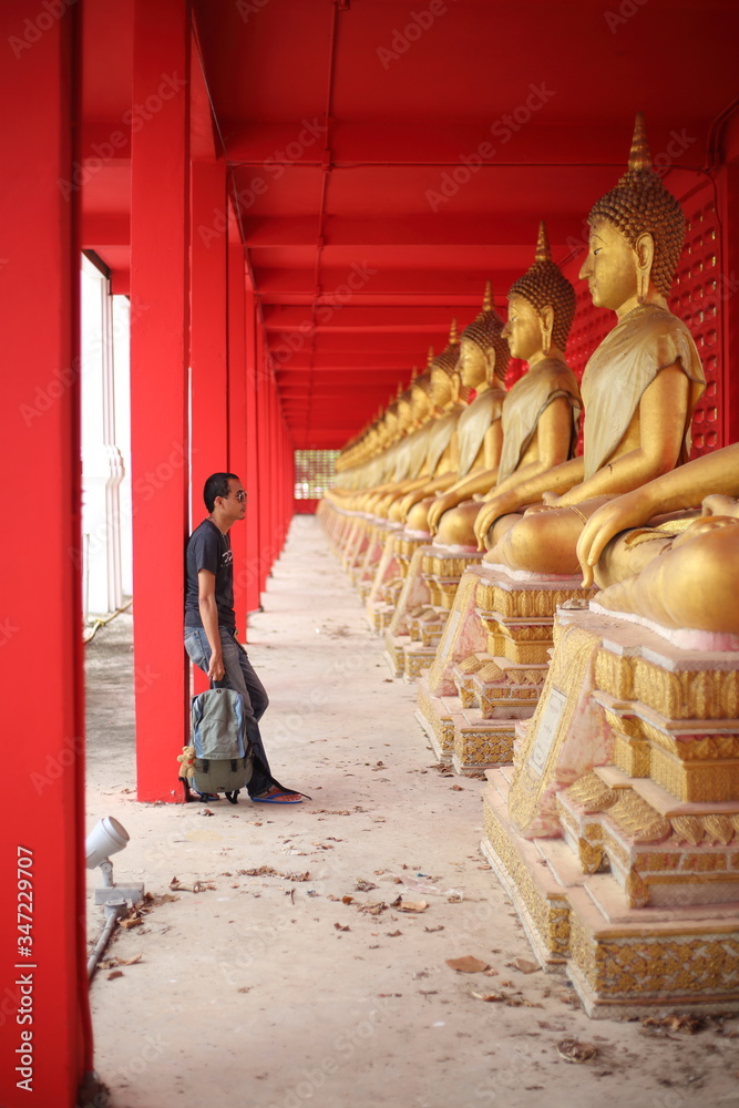 Fototapeta premium Man standing at the line of Buddha statue in Wat Tha Sung, Uthai Thani, Thailand.