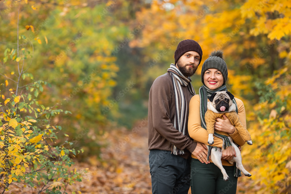 Fototapeta premium happy Family with a dog pug in the autumn forest throws leaves