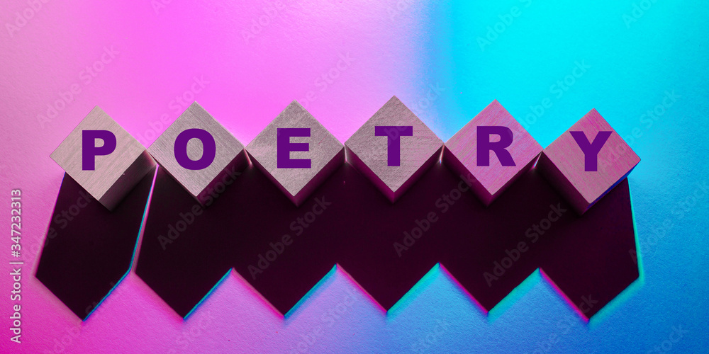 The word poetry is written on wooden blocks on a pink and blue background The word poetry is written on wooden blocks on a pink and blue background