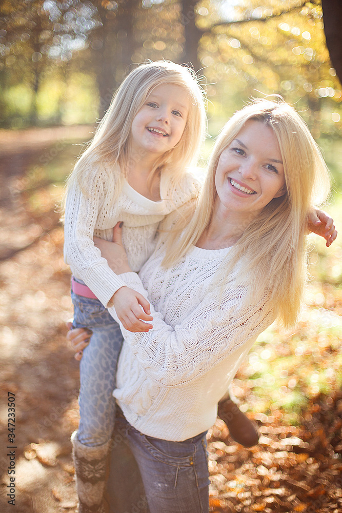 Fototapeta premium Beautiful, happy young mother with little daughter playing in Autumn park.