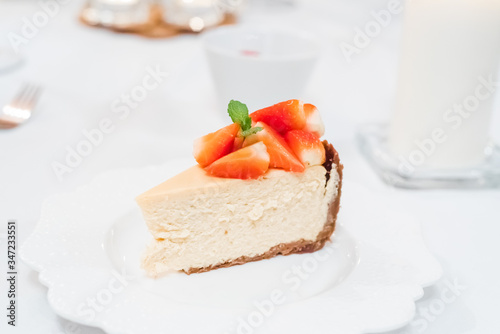 Fresh strawberry cheesecake on a ceramic plate on a white festive table