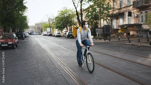Wallpaper Mural Courier with yellow backpack and protective mask rides a bicycle on the street through the city with food delivery and using smartphone Torontodigital.ca
