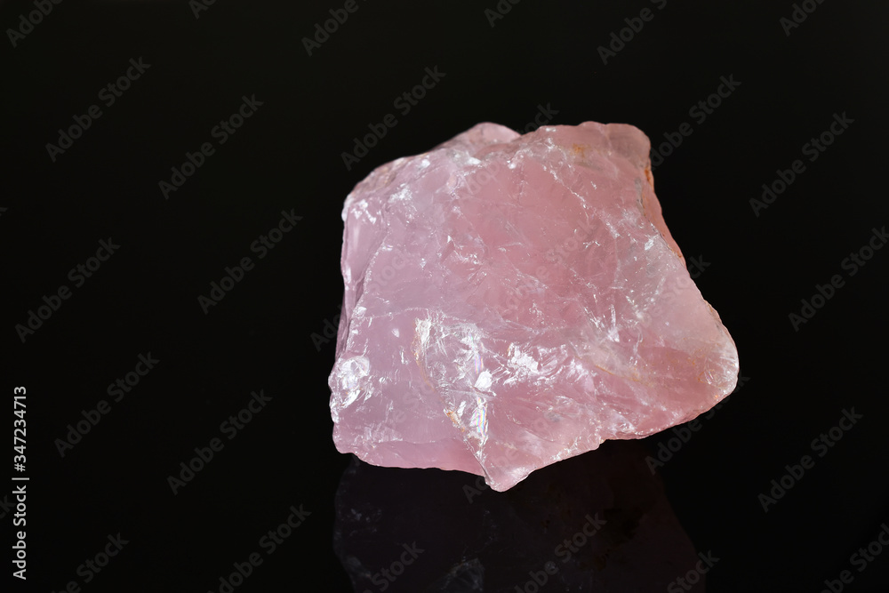 An image of an uncut rose quartz crystal on a black background. An image of an uncut rose quartz crystal on a black background.
