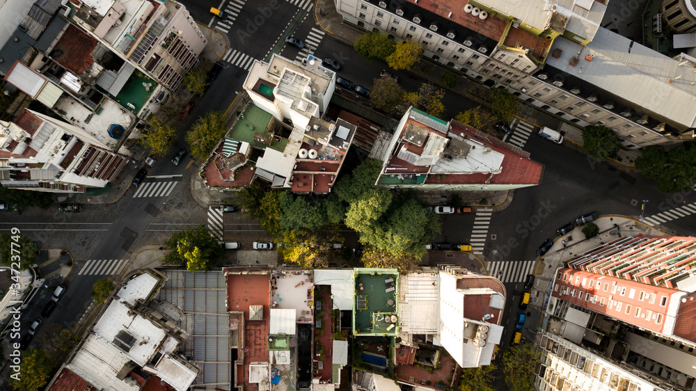 Aerial view of triangle shaped set of the buildings surrounded by streets, pedestrian passing, and autumn trees in the center of the Palermo district in Buenos Aires, Argentina. 