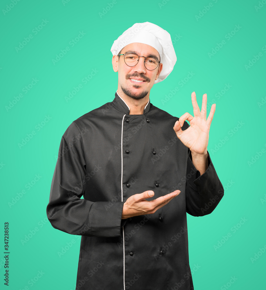 Happy young chef doing an all right gesture Happy young chef doing an all right gesture