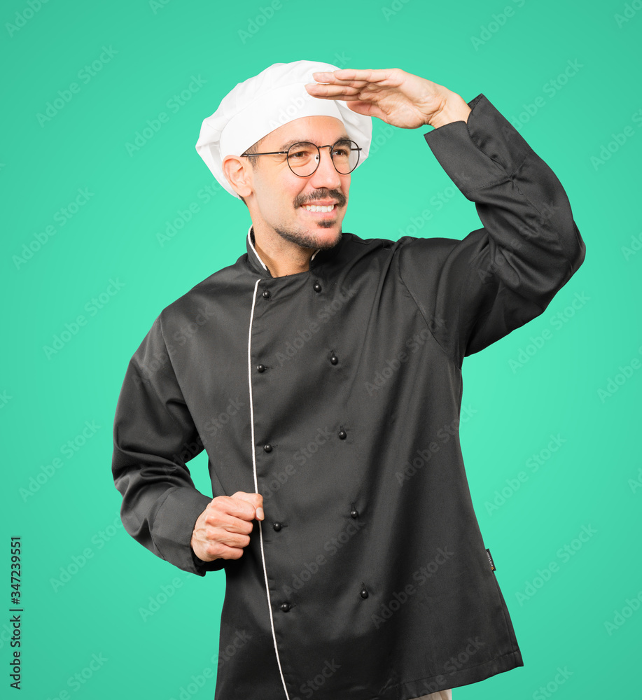 Happy young chef with a gesture of looking away Happy young chef with a gesture of looking away