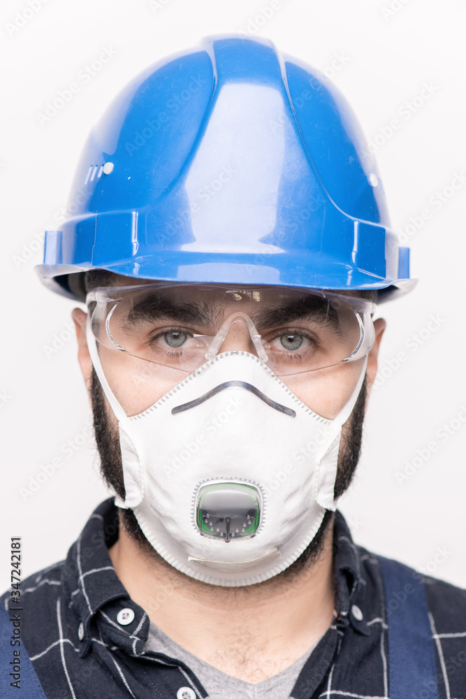 Head of young engineer or builder in hardhat and protective mask looking at you Head of young engineer or builder in hardhat and protective mask looking at you