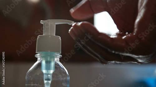 hand rub or sanitiser alcohol solution sprayed in to asian black hand