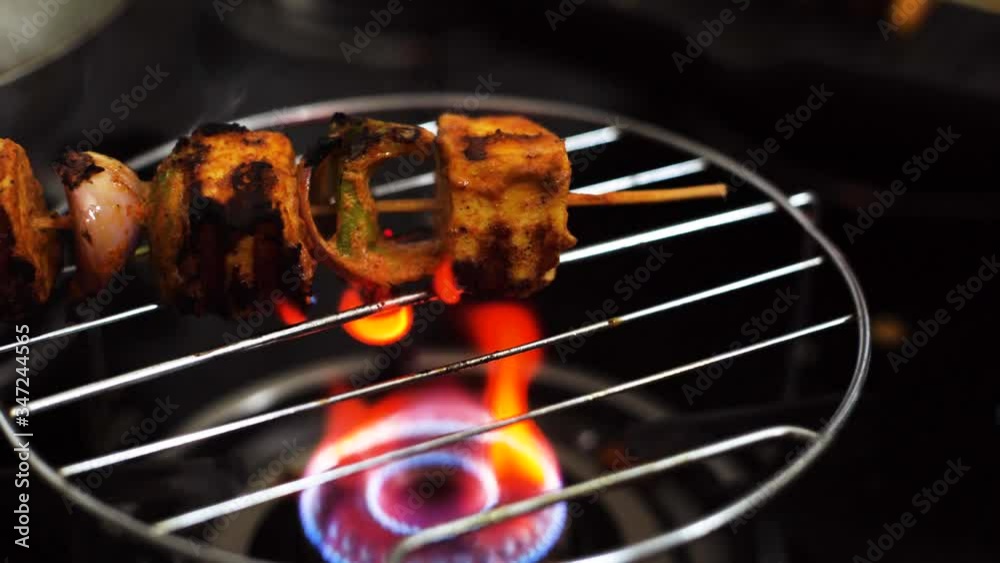 hand turning a skewer of paneer shimla mircha pepper spice onion