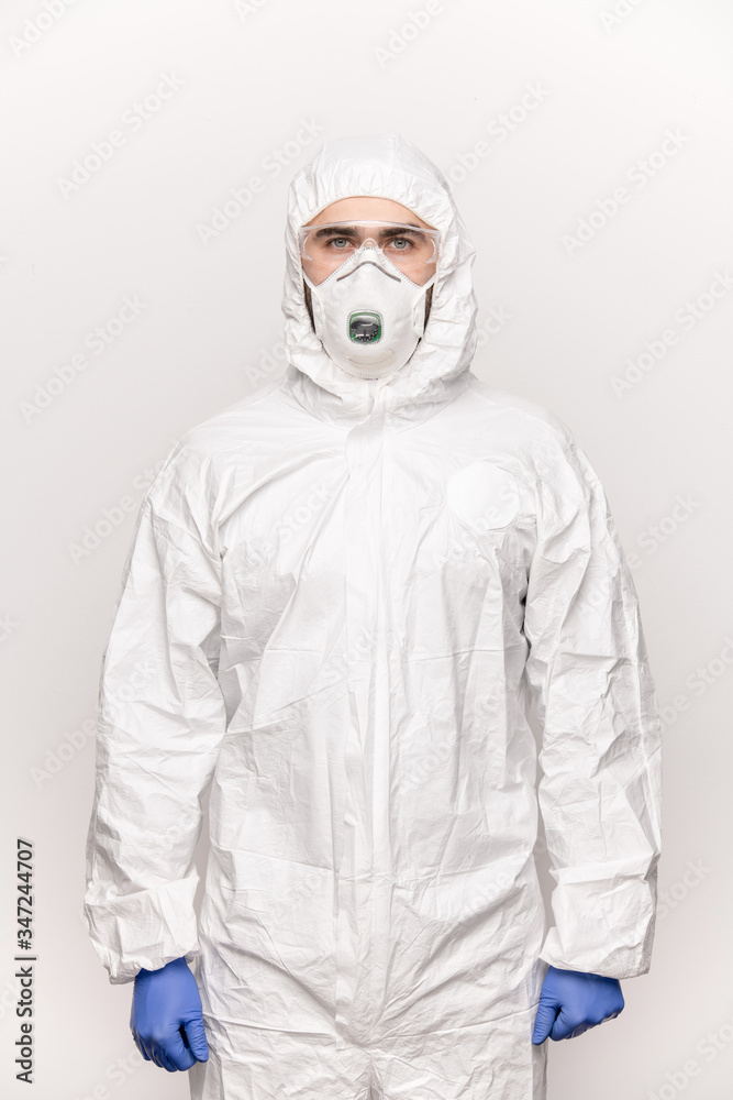 Contemporary young man in protective eyeglasses, blue gloves, mask and coveralls Contemporary young man in protective eyeglasses, blue gloves, mask and coveralls
