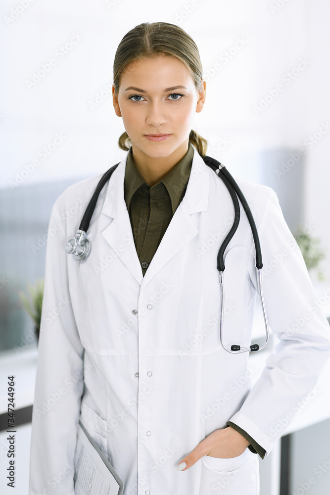 Woman-doctor standing and looking at camera. Perfect medical service in clinic. Medicine and healthcare Woman-doctor standing and looking at camera. Perfect medical service in clinic. Medicine and healthcare