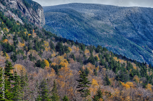 Autumn colors along the shore of Echo lake in New Hampshire with snow and frost on he tops of the White Mountains