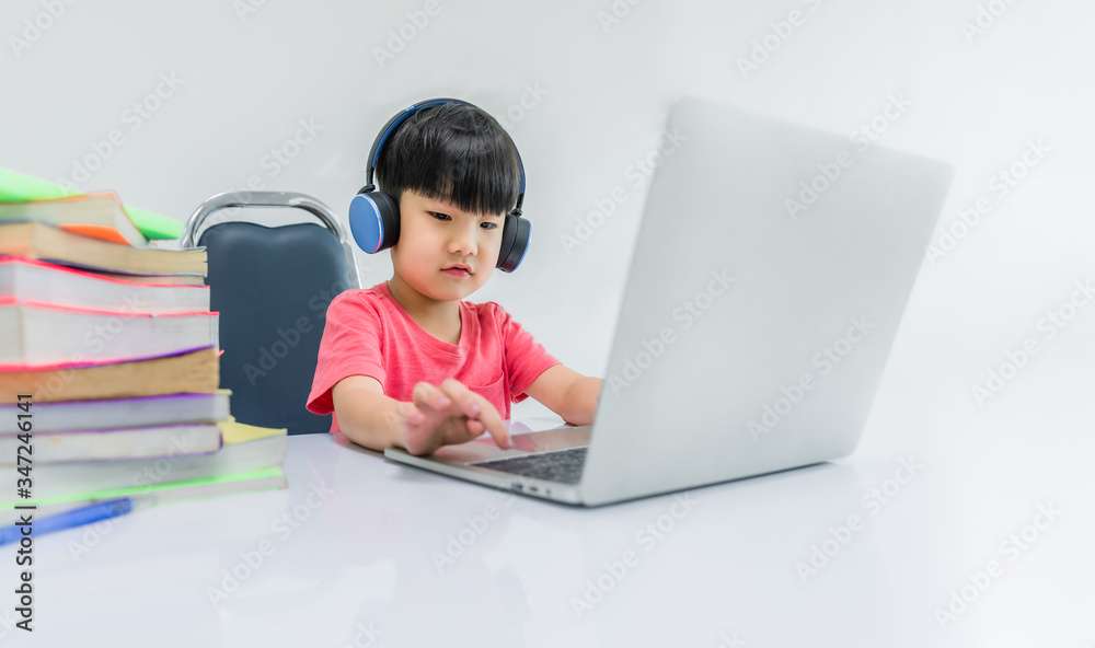 Happy childhood boy wear earphone and enjoy sound and online learning by laptop computer Happy childhood boy wear earphone and enjoy sound and online learning by laptop computer