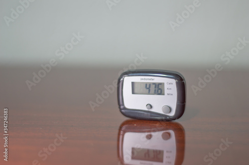 pedometer, step counter for those who practice physical exercises such as walking or running, on a wooden table with several counted steps