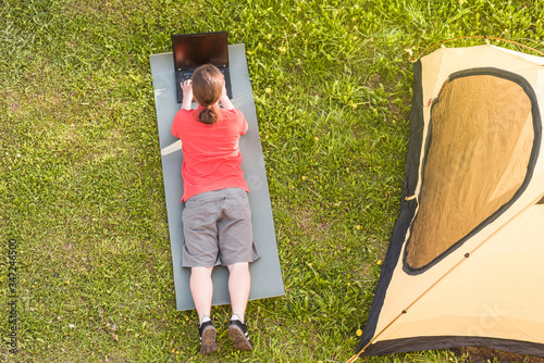 A freelancer uses a laptop in nature. Work in a camping.