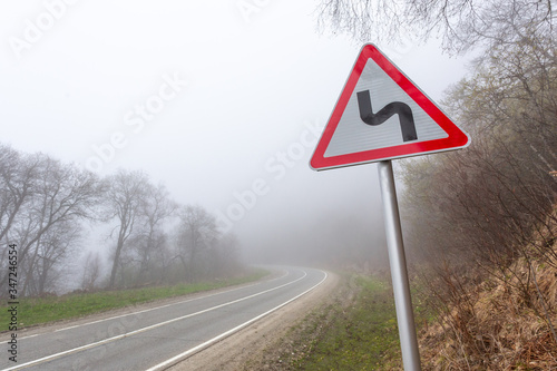 Road sign mountain serpentine. Mountain road in the fog