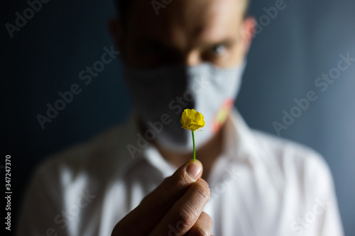 The man in the mask  Stop Coronavirus  sniffs the smell of a fresh flower  COVID-19