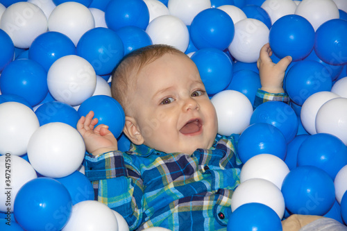 A child in bright balloons. Pool with balls for playing.