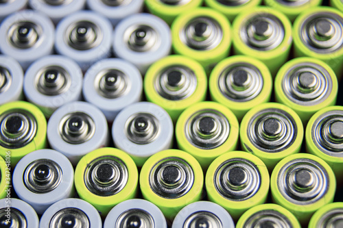 A large number of old AA batteries. The batteries are laid out in a square shape. Batteries form a beautiful background. A variety of power sources. Pattern of batteries laid out in a row.