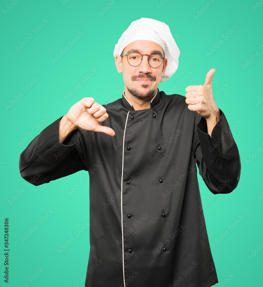 Hesitant young chef gesturing that everything is fine Hesitant young chef gesturing that everything is fine