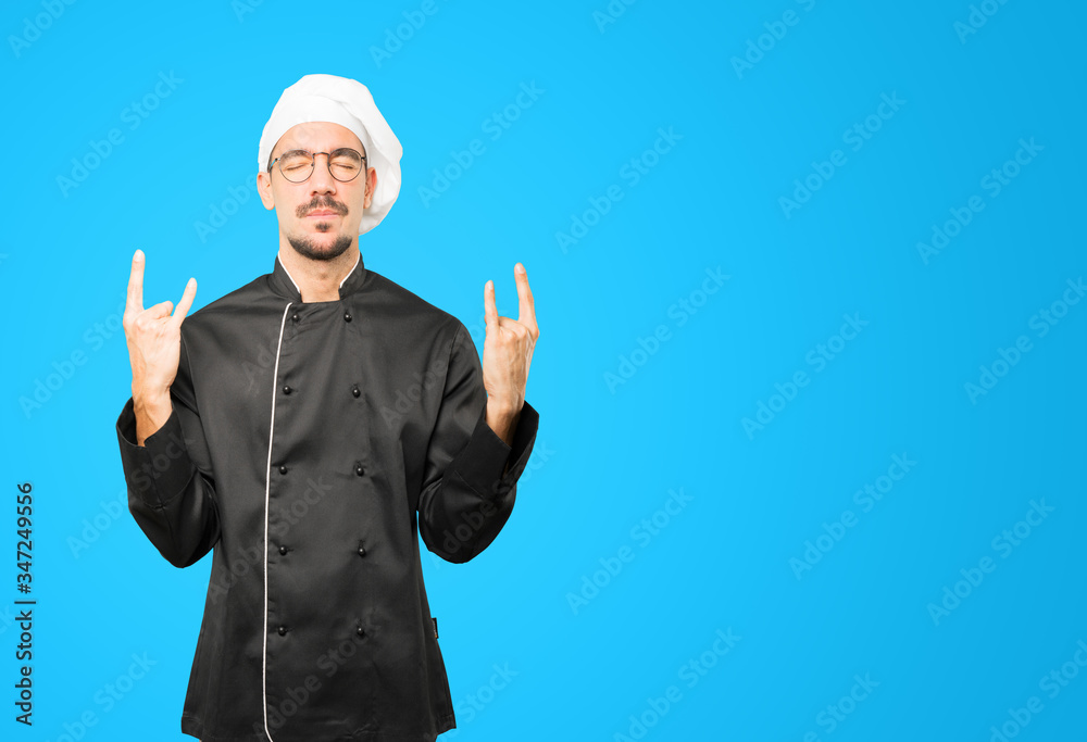 Naughty young chef making a rock gesture Naughty young chef making a rock gesture